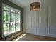 Bright living room featuring large windows, stylish light fixture, and custom wall paneling at 1444 Old Apex Rd, Cary, NC 27513