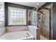 Bright bathroom featuring a soaking tub beneath a patterned glass window and a glass enclosed shower area at 1613 Waddell Ct, Durham, NC 27703