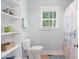 Bright bathroom with a white toilet, open shelving, and a window bringing in natural light at 165 Alpine Rd, Moncure, NC 27559