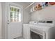 Well-lit laundry room with shelving, modern washer, dryer, and exterior access door at 1998 Ferbow St, Creedmoor, NC 27522