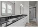 Bright bathroom featuring double vanity with black countertop and framed mirrors, and glass shower enclosure at 2015 Cheek Rd, Durham, NC 27704