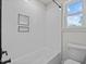 Modern shower with white tile, built-in shelves, and a showerhead, naturally illuminated by a window at 2015 Cheek Rd, Durham, NC 27704