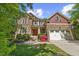 Charming two-story home featuring stone and brick accents, well manicured shrubs, and an attached garage at 208 Bellagio Dr, Apex, NC 27539