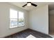 Bright bedroom with large window overlooking neighborhood, featuring hardwood floors and ceiling fan at 2316 Gathering Square Ct, Fuquay Varina, NC 27526