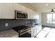 This contemporary kitchen features stainless steel appliances, granite countertops, and modern gray backsplash at 2316 Gathering Square Ct, Fuquay Varina, NC 27526