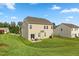 Spacious backyard with lush green lawn, patio area with seating, and neutral colored two-story home under a blue sky at 3832 Stovall Dr, Haw River, NC 27258