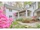 Inviting white home with a spacious covered porch, complemented by colorful flowering bushes and stone pathway at 4 The Gln, Chapel Hill, NC 27514
