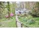 Picturesque white home with charming front porch, surrounded by vibrant landscaping, stone pathway, and lush greenery at 4 The Gln, Chapel Hill, NC 27514