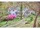Charming white house with a covered front porch, surrounded by lush landscaping and flowering trees at 4 The Gln, Chapel Hill, NC 27514