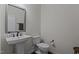 Simple powder room featuring a pedestal sink, a toilet, and dark wood flooring at 433 Triumph Ln, Wake Forest, NC 27587