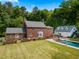 Aerial view of a brick home with in-ground pool surrounded by lush greenery and a detached garage at 500 Old Greensboro Rd, Chapel Hill, NC 27516