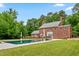 Beautiful brick home with a large in-ground pool, manicured lawn, and mature trees at 500 Old Greensboro Rd, Chapel Hill, NC 27516
