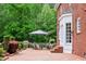 Outdoor brick patio featuring an umbrella-covered dining area, with lush greenery and landscaping surrounding the space at 500 Old Greensboro Rd, Chapel Hill, NC 27516