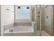 Bright bathroom showcasing a tub beneath a window, and a glass-enclosed shower with stylish gray tiling at 552 Lemon Daisy Ln, Knightdale, NC 27545
