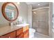 This bathroom offers a glass shower, granite countertops, a wood vanity, and a large, oval mirror at 5713 Old Forge Cir, Raleigh, NC 27609