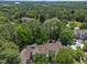 Aerial shot of the condo community shows rooflines with many tall, green trees on a sunny day at 6120 Sunpointe Dr # 102, Raleigh, NC 27606