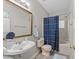 Bathroom features a large mirror, vanity and sink, toilet, and tub with showerhead and patterned curtain at 6120 Sunpointe Dr # 102, Raleigh, NC 27606
