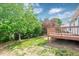 Wooden deck with lush lawn, mature trees, and a sunny sky in the backyard at 7109 Spanglers Spring Way, Raleigh, NC 27610