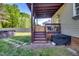 Cozy covered deck with stairs leading to the spacious backyard, including stone pavers, and a cooking area at 827 Lockesley Ln, Burlington, NC 27217