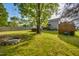 View of large backyard with mature trees, pool, firepit, wooden fence, storage shed, and covered deck area at 827 Lockesley Ln, Burlington, NC 27217