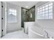 Modern bathroom featuring a soaking tub, walk-in shower with green tile, and natural light at 1009 Sarazen Dr, Clayton, NC 27527