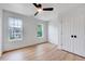 Well-lit bedroom with hardwood floors, a ceiling fan, two windows, and closet at 1009 Sarazen Dr, Clayton, NC 27527