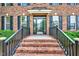 Inviting front entrance with brick steps, black railings, glass door, and manicured shrubbery at 1009 Sarazen Dr, Clayton, NC 27527