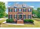 Charming brick two-story home with black shutters, dormers, well-manicured landscaping, and inviting entrance at 1009 Sarazen Dr, Clayton, NC 27527