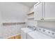 Laundry room with cabinets, wood shelving, wallpaper, and front loading washer and dryer at 1009 Sarazen Dr, Clayton, NC 27527
