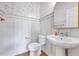 Chic powder room with wainscoting, patterned wallpaper, and pedestal sink with gold accents at 1009 Sarazen Dr, Clayton, NC 27527