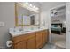 Bright bathroom featuring double sinks with wood cabinets, a wooden framed mirror, and a doorway at 105 Oak Ridge Rd, Franklinton, NC 27525
