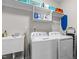 Functional laundry room with white washer and dryer, utility sink, and storage shelving at 105 Oak Ridge Rd, Franklinton, NC 27525