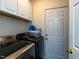 This laundry room features white upper cabinets and side-by-side washer and dryer at 1106 Purple Glory Dr, Apex, NC 27502