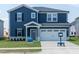 Two-story home featuring navy blue siding, a white two-car garage door, and manicured front lawn at 1112 Landen Creek Ln, Zebulon, NC 27597