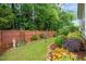 Secluded backyard with green grass, garden beds, mature landscaping, and a privacy fence at 1408 Fairmont St, Durham, NC 27713