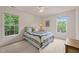 Cozy bedroom featuring two windows, neutral carpet, ceiling fan and beautiful quilting on the bedspread at 1408 Fairmont St, Durham, NC 27713