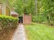 Lush backyard with walkway to private brick courtyard with black metal gate and brick privacy wall at 1428 Gray Bluff Trl, Chapel Hill, NC 27517
