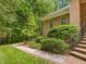 Charming exterior of a brick home with a stone walkway surrounded by mature landscaping and trees at 1428 Gray Bluff Trl, Chapel Hill, NC 27517