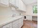 Well-lit laundry room with a utility sink, ample counter space, and custom cabinets at 1428 Gray Bluff Trl, Chapel Hill, NC 27517