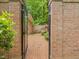 Brick-paved walkway to private courtyard featuring an ornate, secured gate and lush greenery at 1428 Gray Bluff Trl, Chapel Hill, NC 27517