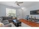 Bright living room with a comfortable gray sofa, a ceiling fan, and a modern entertainment center at 1710 Grace Point Rd, Morrisville, NC 27560
