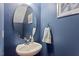 Stylish powder room featuring a modern vanity, a large round mirror, and elegant blue walls at 1710 Grace Point Rd, Morrisville, NC 27560