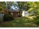 Lawn view featuring the brick home, a white storage shed and lush landscaping in the backyard at 210 S Hughes St, Apex, NC 27502