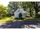 View of the backyard with the brick home and white storage shed surrounded by mature trees and green lawn at 210 S Hughes St, Apex, NC 27502