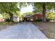 View of the backyard with a driveway leading up to the brick home and carport at 210 S Hughes St, Apex, NC 27502