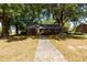 Quaint brick home featuring mature trees, green lawn and a walkway leading to the front door at 210 S Hughes St, Apex, NC 27502