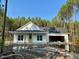 New construction home featuring white siding, a covered porch, and an attached garage, surrounded by a lush treeline at 214 Green Pines Estates Dr, Kenly, NC 27542