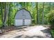Two-car detached garage with white doors and decorative detailing against a lush, green backdrop at 220 Cardinal Dr, Youngsville, NC 27596