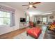 Bright living room with hardwood floors, ceiling fan, large windows, and a stylish red ottoman at 220 Cardinal Dr, Youngsville, NC 27596