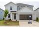 Two-story home with light gray siding, open garage, and a manicured front lawn with young tree at 2230 Cherry Creek Rd, Haw River, NC 27258